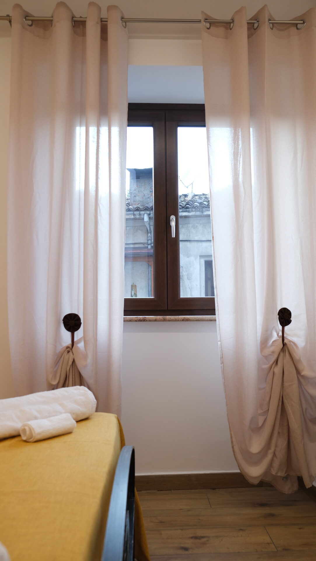 Finestra con tende e vista sui tetti del borgo