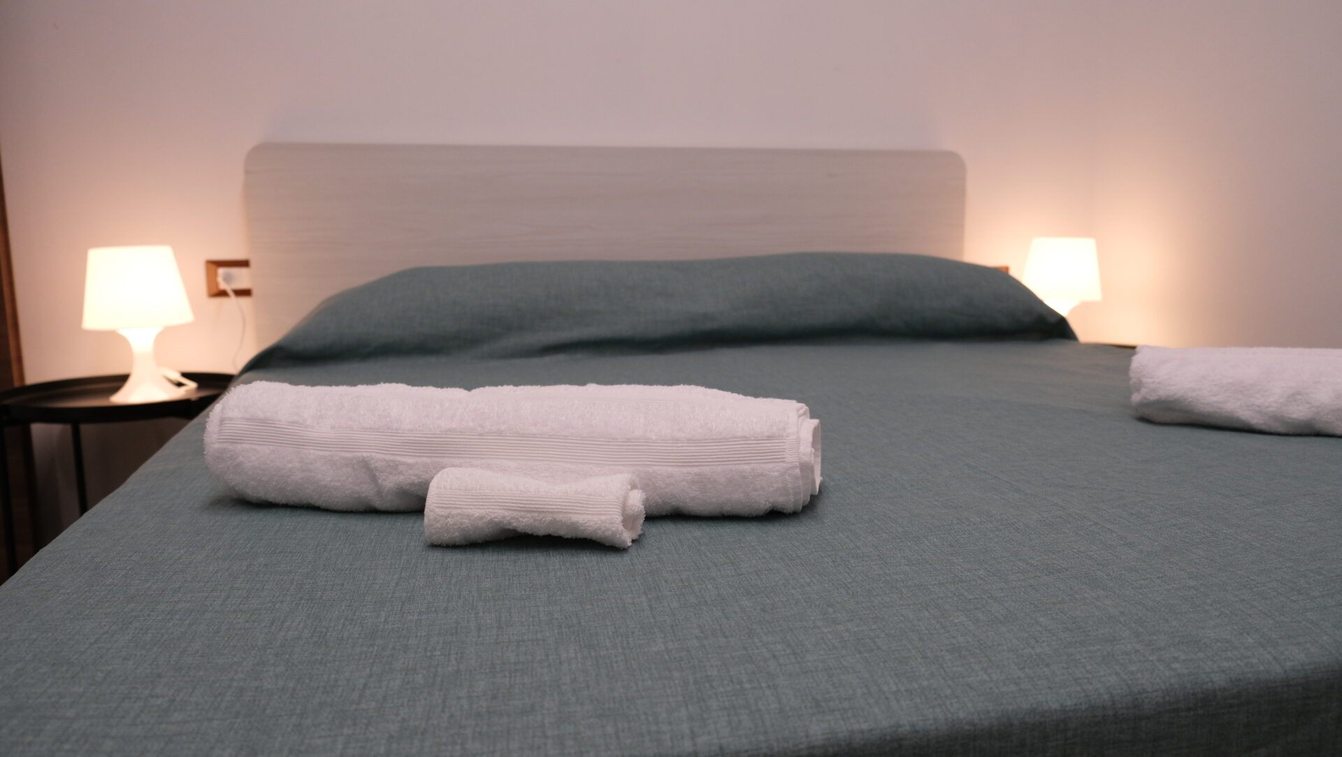Letto della camera Alba con biancheria verde e asciugamani preparati