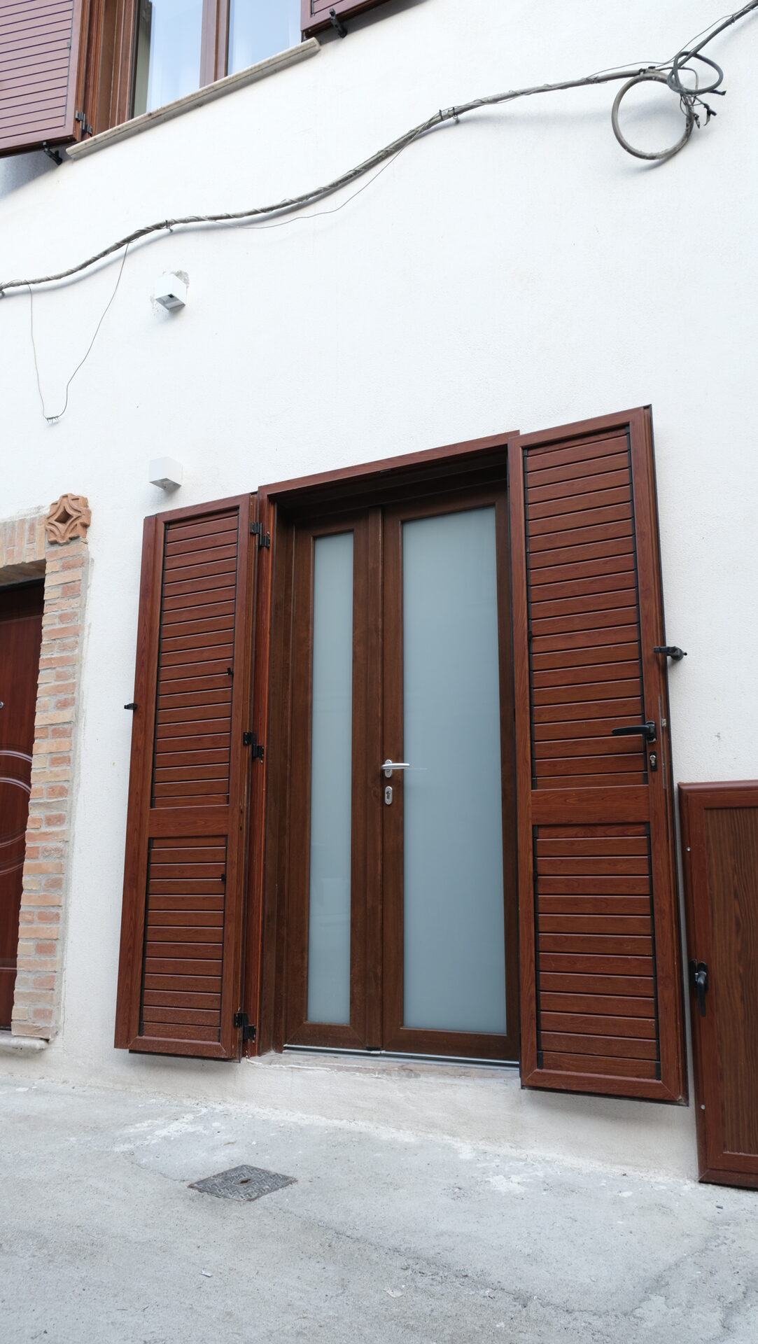 Porta d'ingresso e finestre con persiane in legno